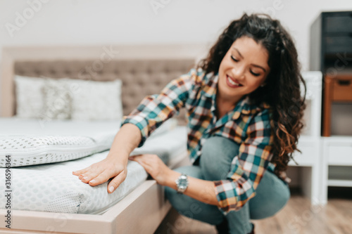 Beautiful and happy middle age woman choosing new bed and mattress in big furniture store