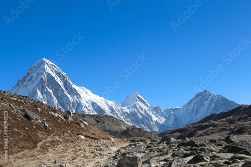 Route to Everest base camp near Khumbu glacier with clear blue sky. Pumori, Lungtren and Khumbutse mountain peaks are visible in the background. photo