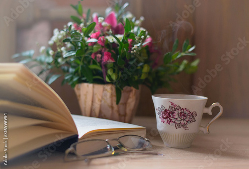 Spring pastel peaceful still life with green bouquet porcelain cup of hot coffee  open book and glasses