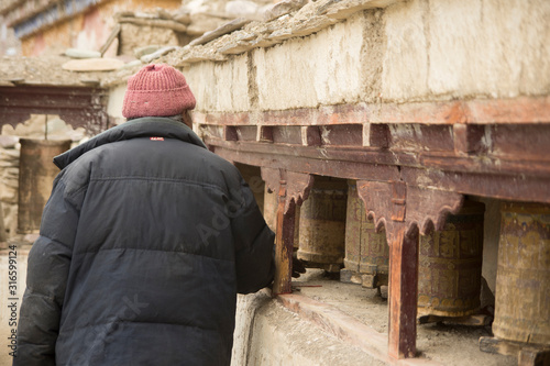 man spining prayer wheels in lamayuru monastery, ladakh, india