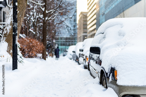 Parallel parked cars covered in snow with lone woman on side walk  © derek