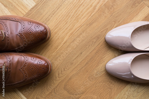 stylish leather shoes of a man and of a woman on wooden floor