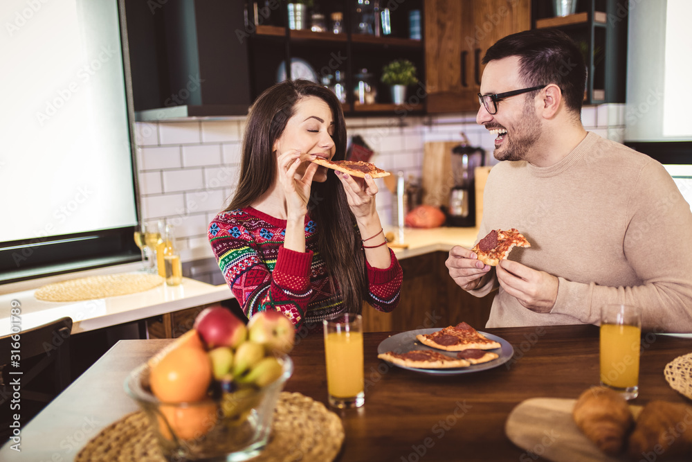 Young couple enjoying eating pizza at home. Young couple enjoying eating pizza at home.