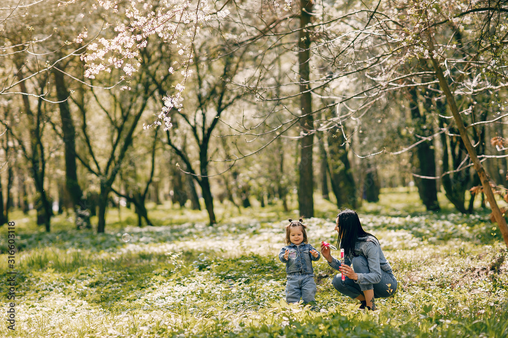 Beautiful mother with daughter. Family in a spring park. Woman in a blue jacket