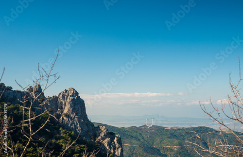Mountain landscape and wind turbines in the background.