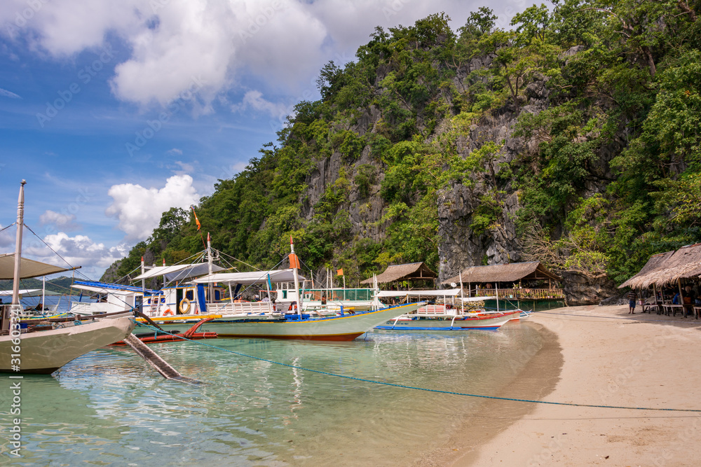 Traditional wooden Filipino boats by the beach of a small island in the sea, Coron Palawan Philippines