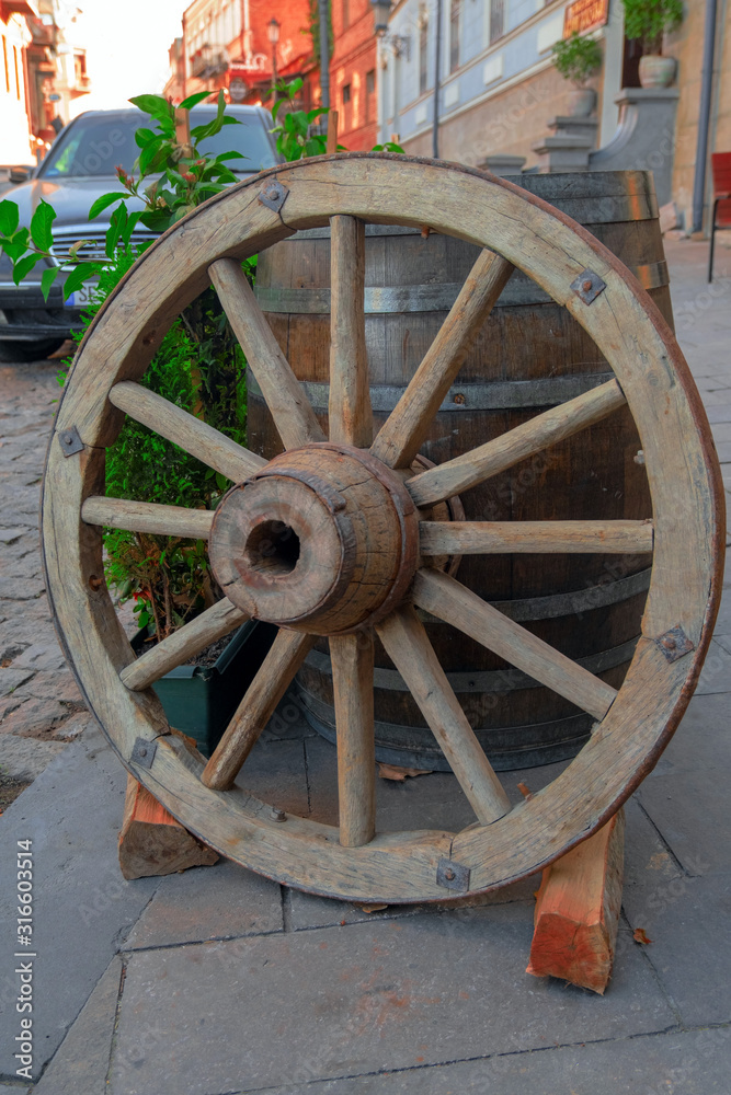 an old wooden shabby cartwheel used as the decor of a restaurant window on the tourist street of the old city