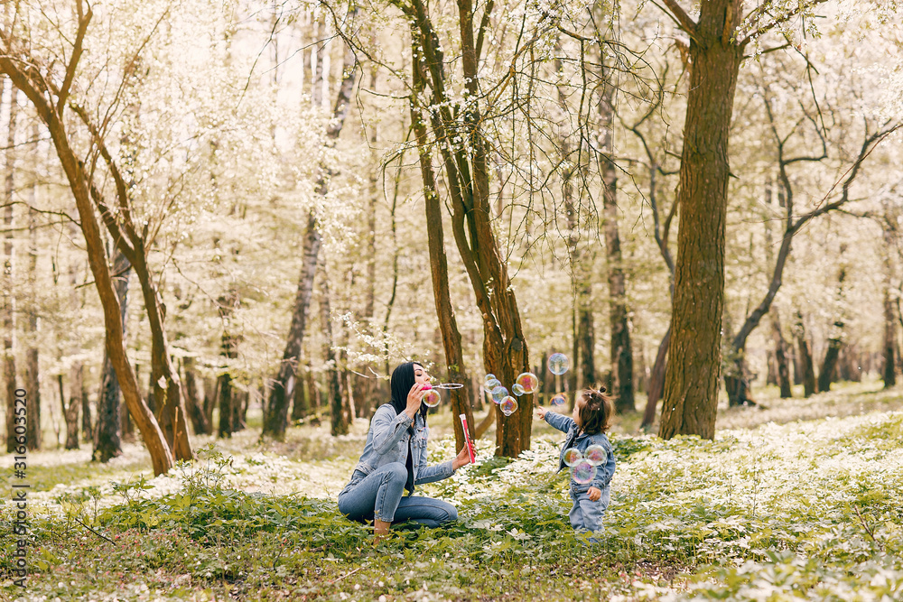 Beautiful mother with daughter. Family in a spring park. Woman in a blue jacket Beautiful mother with daughter. Family in a spring park. Woman in a blue jacket