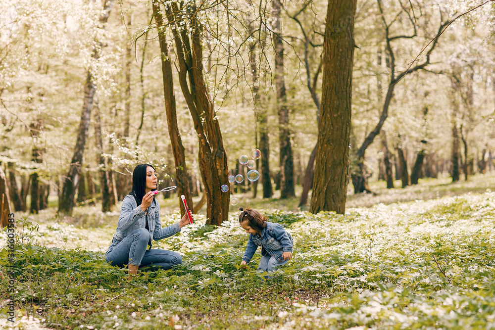 Beautiful mother with daughter. Family in a spring park. Woman in a blue jacket Beautiful mother with daughter. Family in a spring park. Woman in a blue jacket