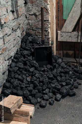 Photography Coal, wood and shovel on the floor at the basement prepared for heating the house with