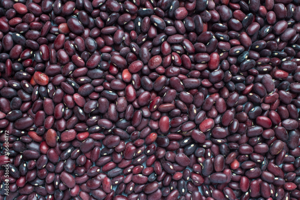Unfocused red beans completely scattered in an even layer on a flat surface. Natural close-up background with space for copying Unfocused red beans completely scattered in an even layer on a flat surface. Natural close-up background with space for copying