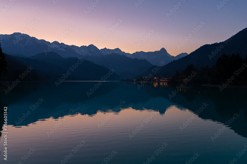 Alps silhouette in reflection in the lake Barcis, Italy
