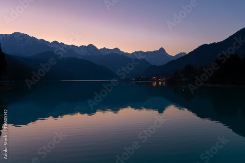 Alps silhouette in reflection in the lake Barcis, Italy