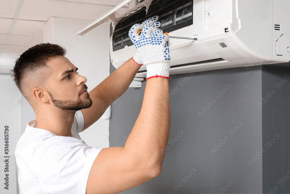 Male technician repairing air conditioner indoors - obrazy, fototapety, plakaty 
