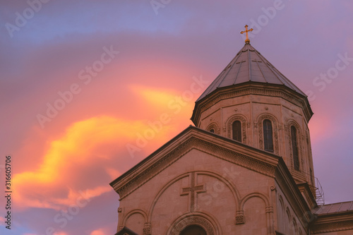 detail of an old Christian Church, tower on a sunset background with pink clouds