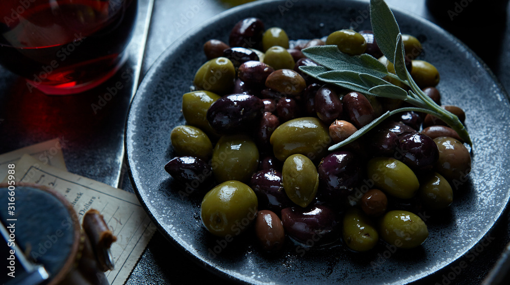 Small plate of grean and black olives with sage leaf garnish Small plate of grean and black olives with sage leaf garnish