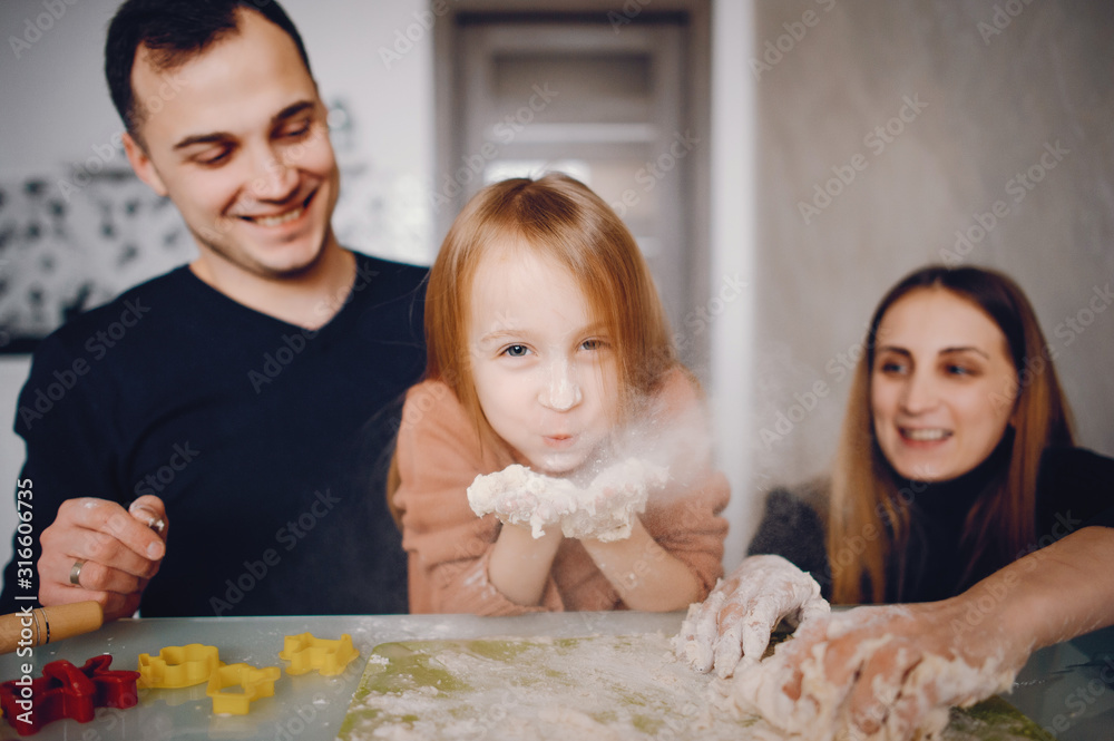 Family in a kitchen. Little girl with a dough.