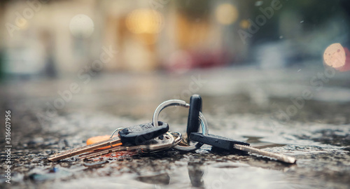 Set of lost keys on the ring on wet ground on the street