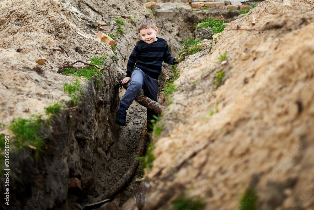 A trench dug in the ground in which a little boy plays. A trench dug in the ground in which a little boy plays.