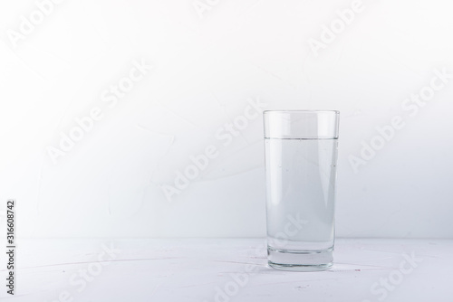 transparent glass with water on a pink table and white concrete background