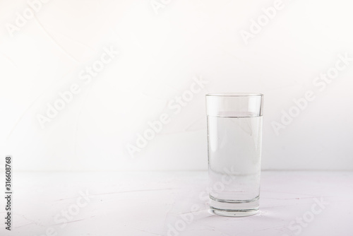 transparent glass with water on a pink table and white concrete background