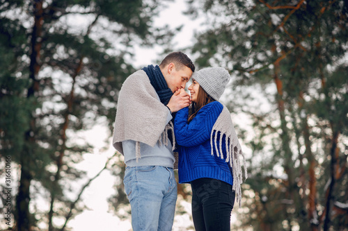 Couple in a winter forest. Beautiful girl in a blue sweater. © hetmanstock2