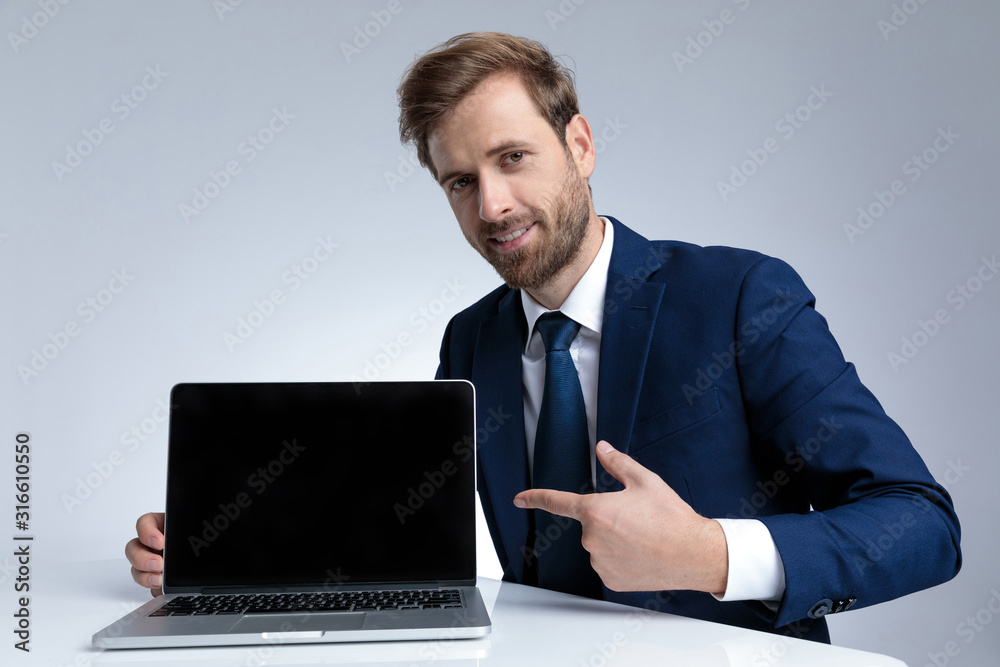Young businessman smiling and pointing to his laptop Young businessman smiling and pointing to his laptop