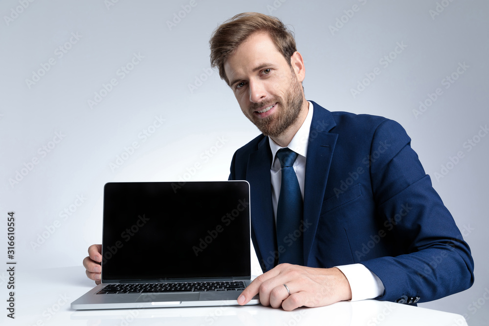 Handsome businessman presenting his laptop while wearing a blue suit Handsome businessman presenting his laptop while wearing a blue suit