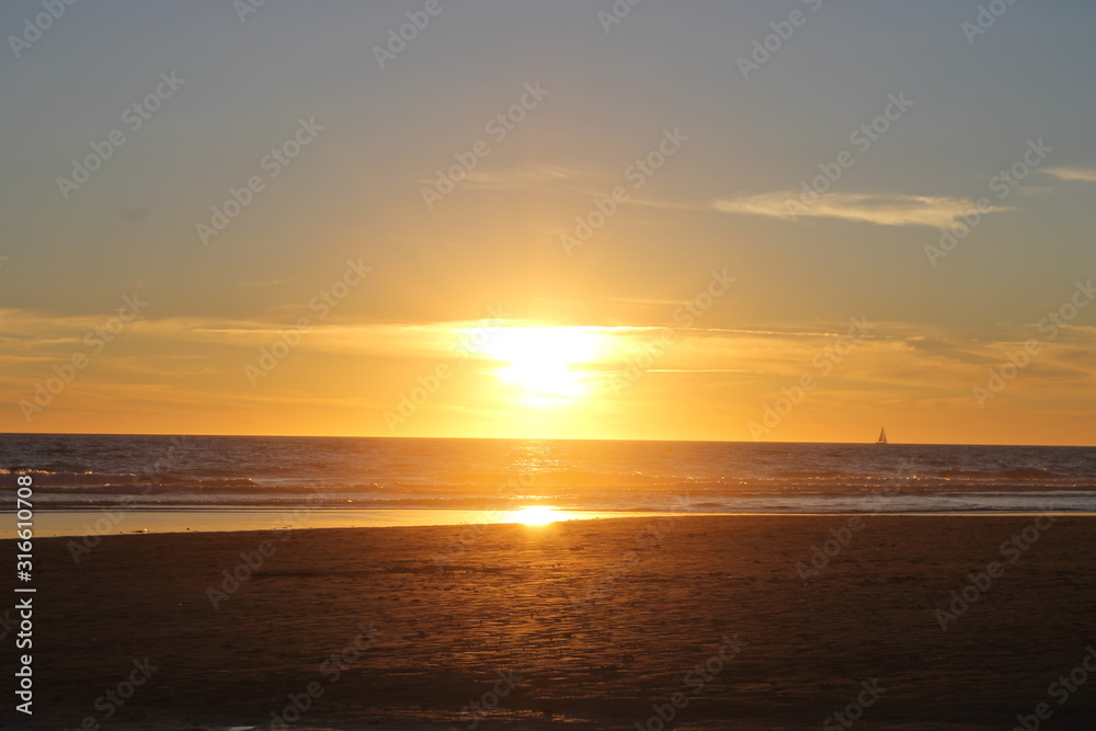 Puesta de sol en una playa del sur de España con un barco al fondo.