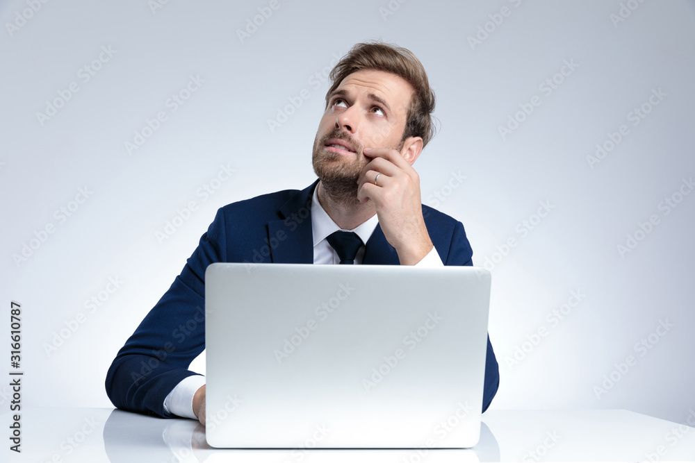 Pensive businessman looking up with his hand on his cheek Pensive businessman looking up with his hand on his cheek