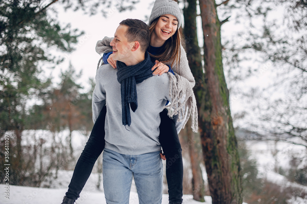 Couple in a winter forest. Beautiful girl in a blue sweater.