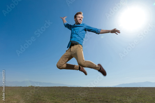 Obraz na plátně casual man wearing blue shirt jumping high to the sky