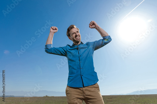 casual man standing with fists up and looking away happy
