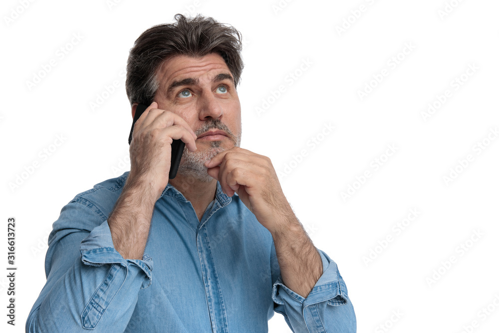 Thoughtful casual man talking on his phone, looking up Thoughtful casual man talking on his phone, looking up