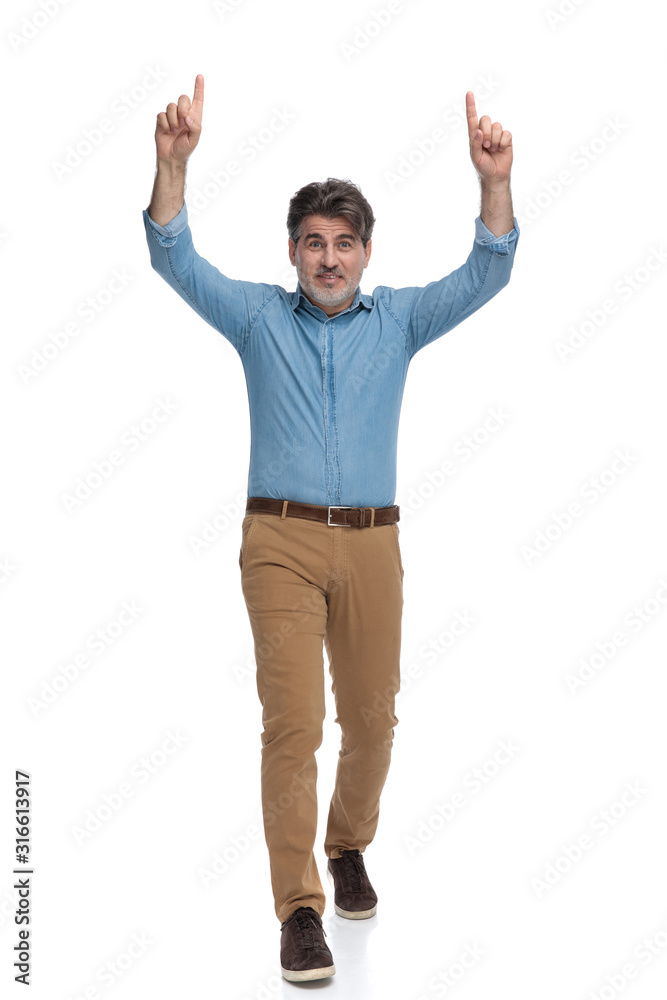 Cheerful casual man pointing up with both hands