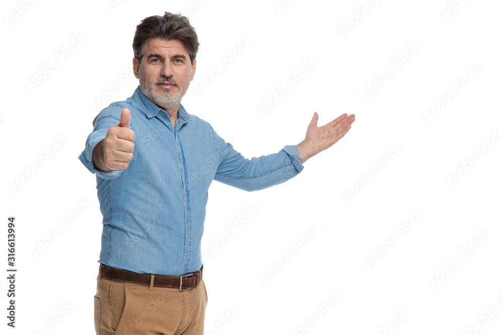 Positive casual man presenting and giving a thumbs up