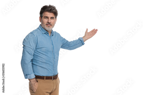 Friendly casual man presenting with a hand in his pocket