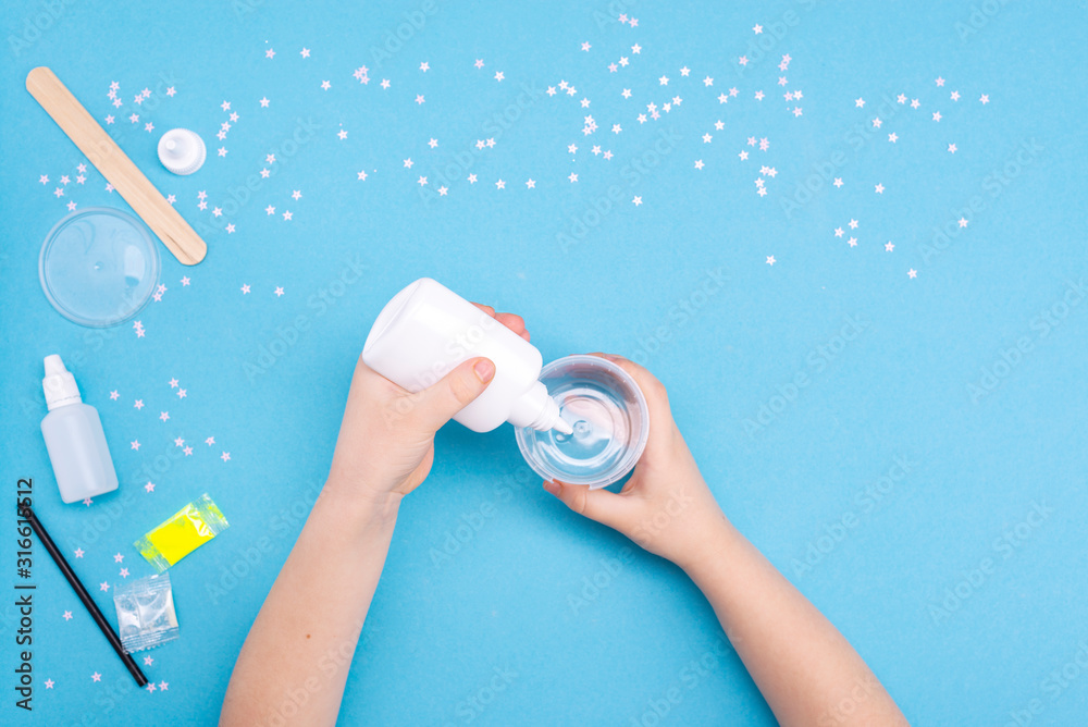 How to make mucus at home. Children's art project. DIY concept. Children's hands making slime toy on blue. Step by step photo instruction How to make mucus at home. Children's art project. DIY concept. Children's hands making slime toy on blue. Step by step photo instruction