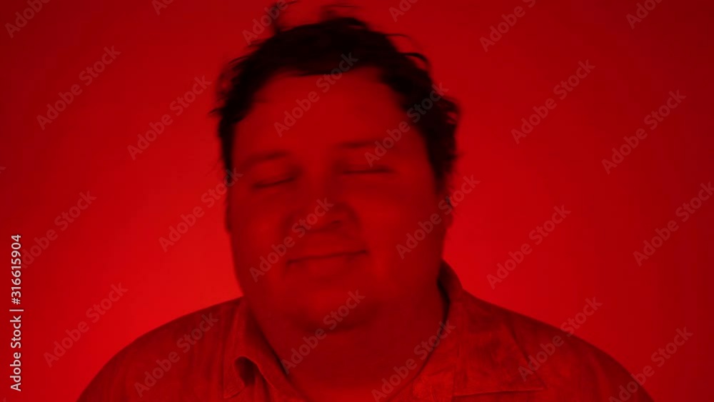 Red lighting: european man smiling and dancing in excellent mood Red lighting: european man smiling and dancing in excellent mood