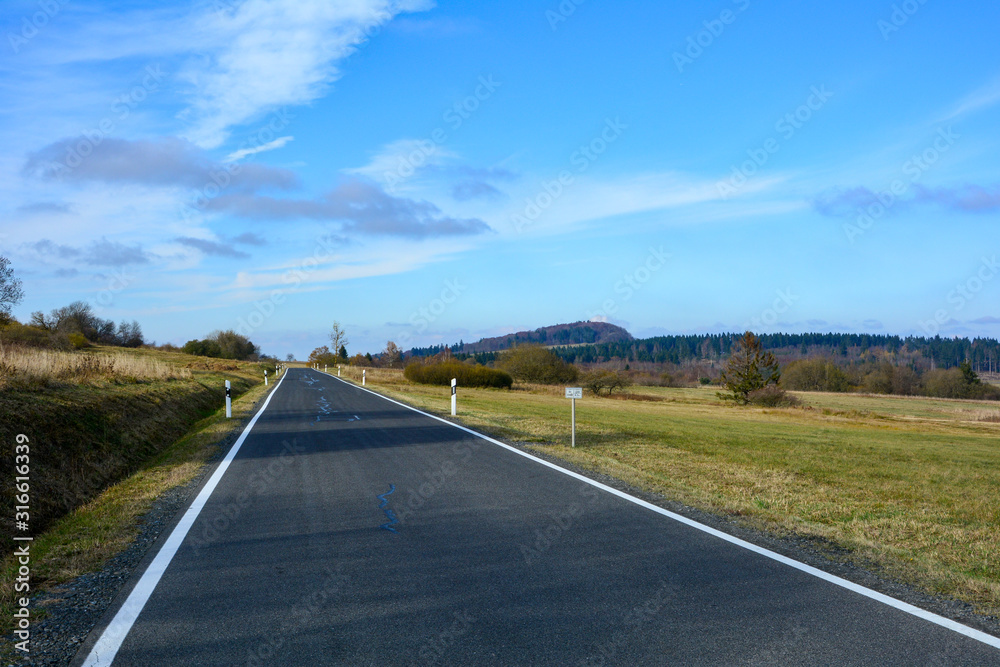 Lonely road through a green landscape, with many blue sky in the Rhoen, Bavaria, Germany