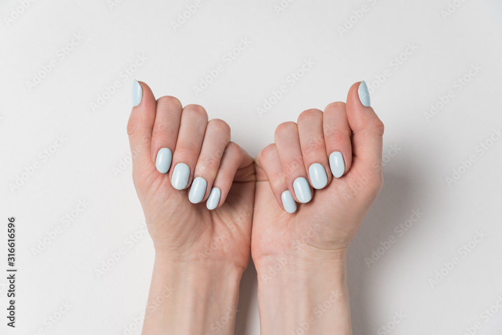 Gentle feminine manicure, blue gel polish. Hands on white background. Gentle feminine manicure, blue gel polish. Hands on white background.