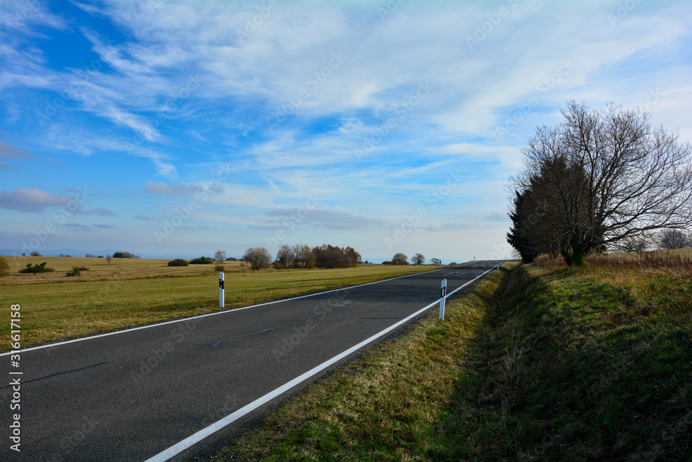 Fototapeta premium A lonely road through a green landscape, in the Rhoen, Germany