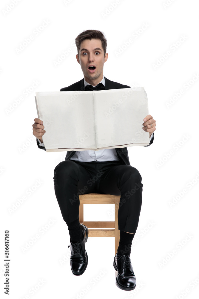shocked young model reading newspaper and sitting shocked young model reading newspaper and sitting