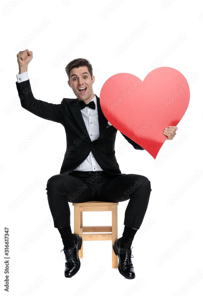 young elegant man celebrating victory and holding big heart young elegant man celebrating victory and holding big heart