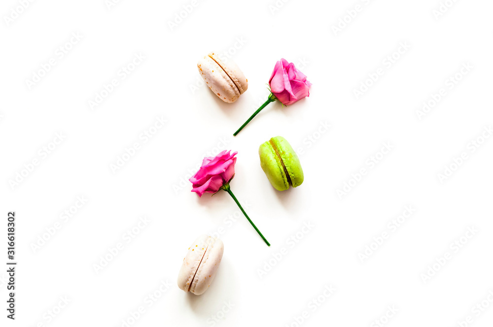 Festive composition. Multicolored macaroons and rose flowers on isolated white background. Festive composition. Multicolored macaroons and rose flowers on isolated white background.