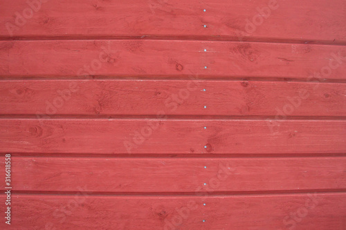 Wooden horizontal boards with cracks and knots are painted red. Background, texture.