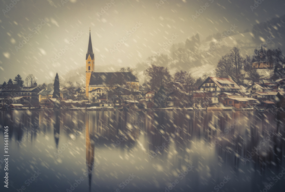 Fototapeta premium The beautiful lake Schliersee in the south of bavaria, germany, with a nice town and a church in the back - heavy snowfall