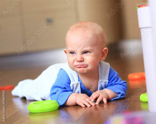 angry baby boy learning to crawl and unhappy crying on the floor