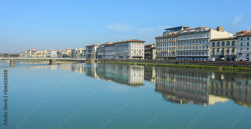 Naklejka premium Arno River and the old promenade in Florence. Hazel houses with red roofs in Florence. Houses are reflected in the water.