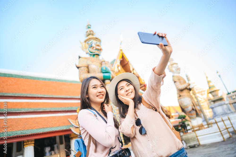 tourist women friends enjoy taking selfie in temple of the emerald buddha, Thailand